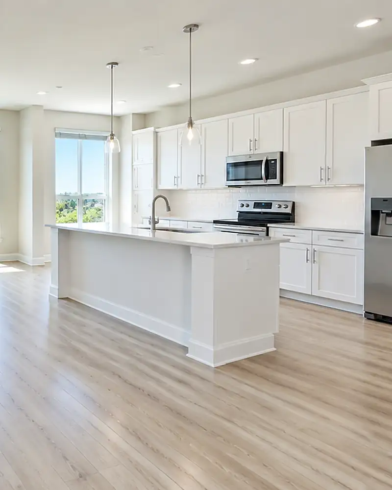 Empty apartment with clean floors, white cabinets and a kitchen island