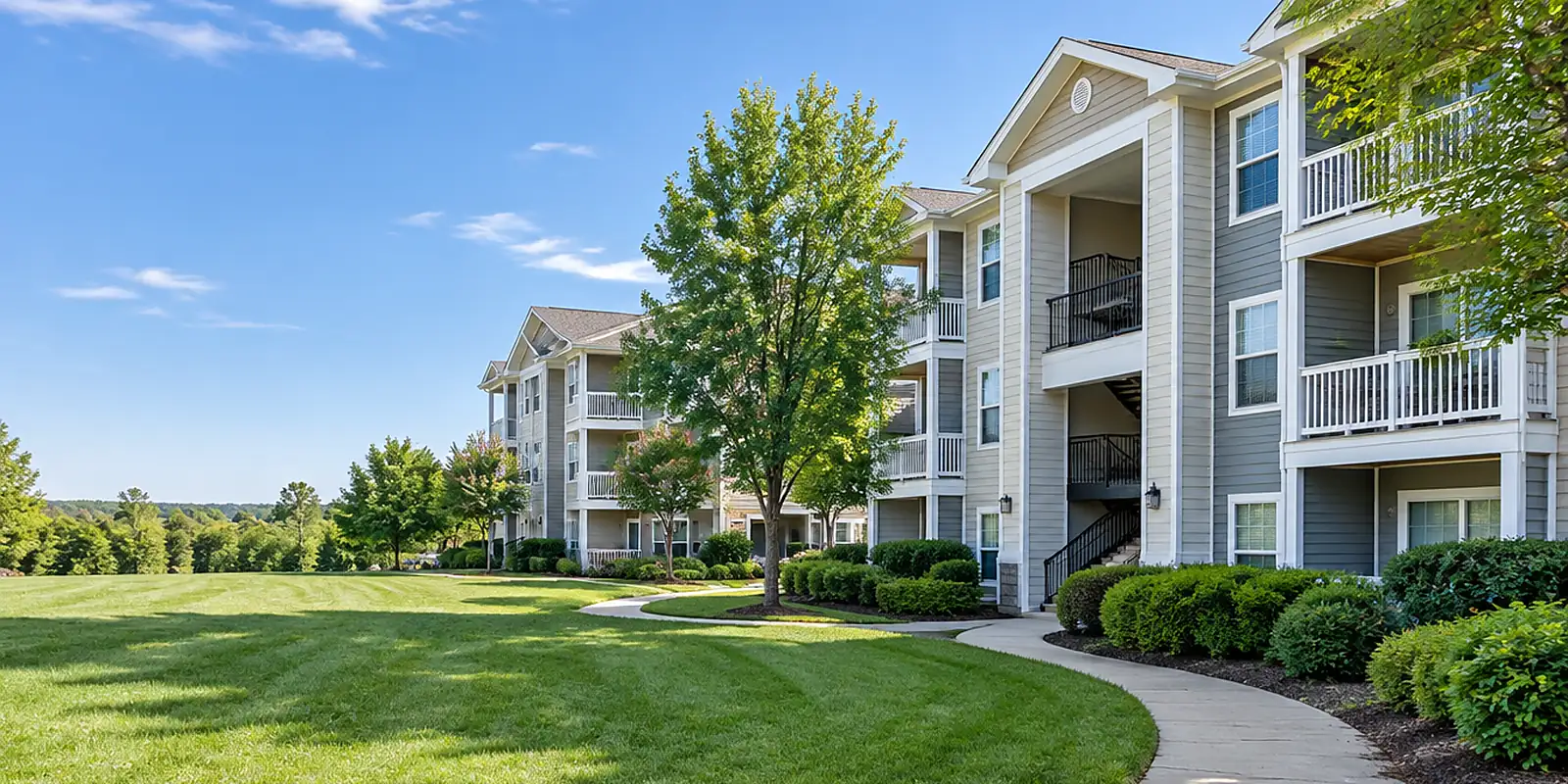 Apartment community buildings with trimmed hedges and a green lawn