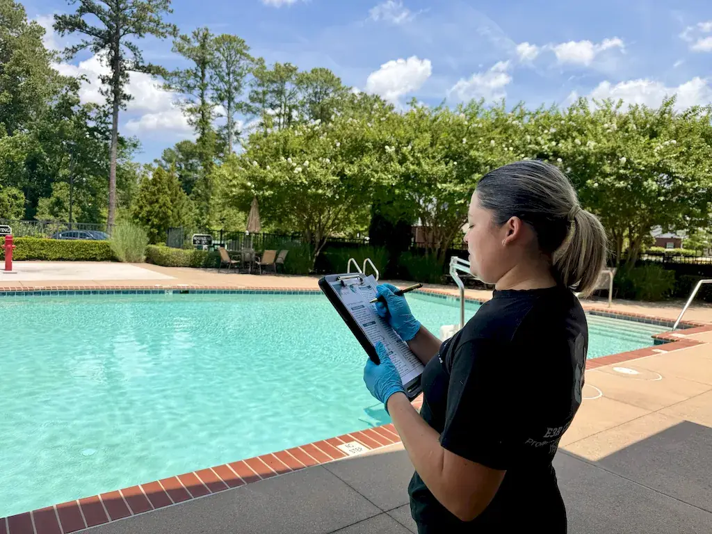 E3R Cleaning team lead checking a checklist on a clipboard beside an apartment community pool
