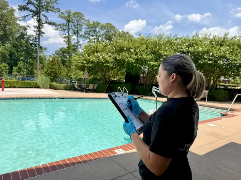 E3R Cleaning team lead checking a tablet checklist beside an apartment community pool