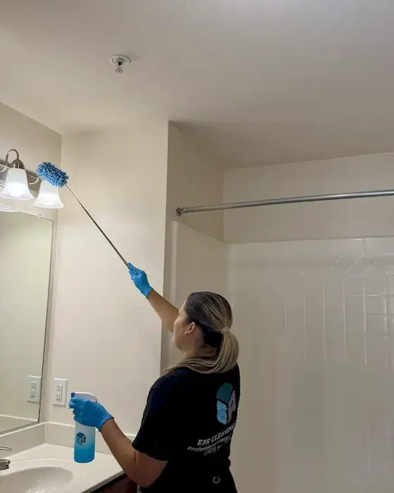 E3R team member dusting high on a wall after construction