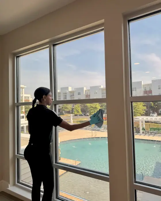 E3R team member cleaning a large window with a pool outside